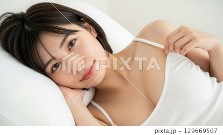 ベッドで横になりキャミソールの肩紐に優しく触れる女性 ベッドで横になりキャミソールの肩紐に優しく触れる女性 129669507