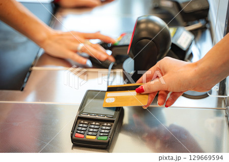 Woman paying with credit card using pos terminal in supermarket 129669594