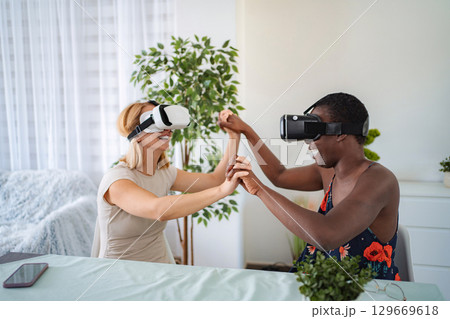 Two joyful friends playing and having fun with virtual reality headsets 129669618