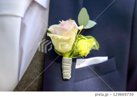 Elegant boutonniere displayed on a suit pocket in a formal setting during a wedding ceremony 129669730