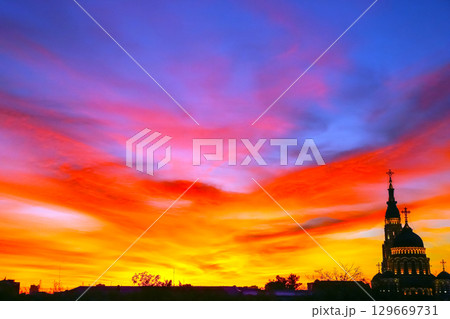 Vibrant sunset over a church in a quiet town showcasing a spectrum of colors Vibrant sunset over a church in a quiet town showcasing a spectrum of colors 129669731