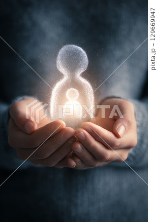 Hands holding glowing figures representing inner child concept with soft light and warmth 129669947