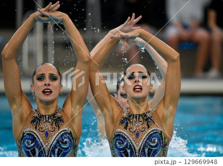 Synchronized swimmers performing a routine in a pool with vibrant costumes and dynamic movements 129669948