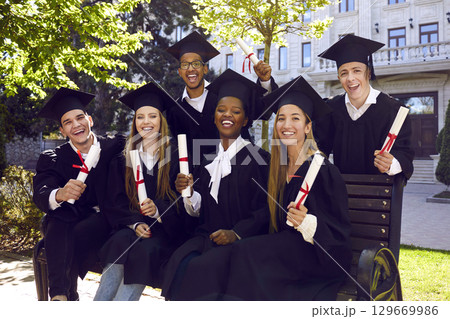 Group of joyful university graduates with their diplomas pose for memorable photo. Group of joyful university graduates with their diplomas pose for memorable photo. 129669986