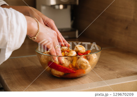 Preparing fresh vegetables in a glass bowl for cooking in a cozy kitchen setting Preparing fresh vegetables in a glass bowl for cooking in a cozy kitchen setting 129670209