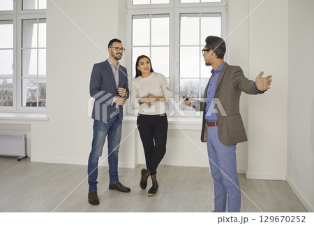 Realtor showing house to a young happy couple. Real estate market concept. 129670252