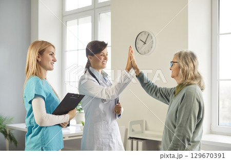Image of female doctor giving high five to mature woman patient Image of female doctor giving high five to mature woman patient 129670391