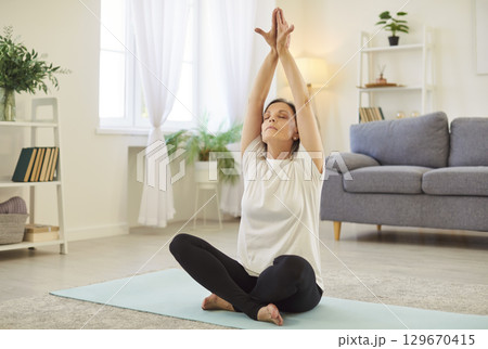 Senior woman in yoga lotus pose at home, learning basic poses, breathing techniques, practice Senior woman in yoga lotus pose at home, learning basic poses, breathing techniques, practice 129670415