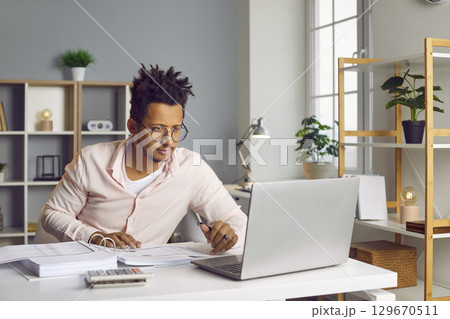 Young business man working on a laptop at office and looking on a computer screen. 129670511