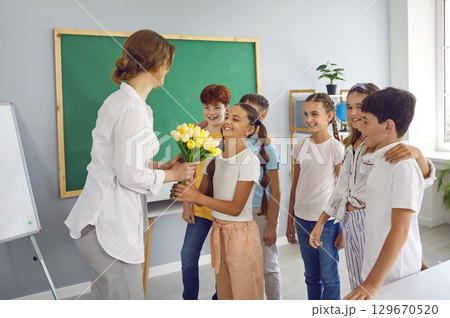 Teacher's Day. Elementary school children give the teacher a bouquet of flowers for the holiday. Teacher's Day. Elementary school children give the teacher a bouquet of flowers for the holiday. 129670520
