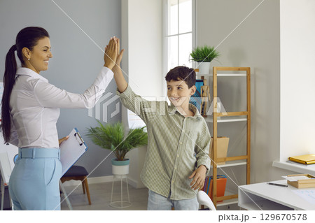 Happy psychologist and a school boy high five each other after a successful therapy session 129670578