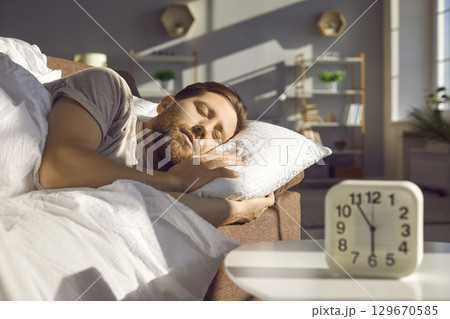Guy is sleeping sweetly, lying in his cozy bed at home in the living room. Guy is sleeping sweetly, lying in his cozy bed at home in the living room. 129670585