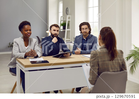 People from human resources commission sitting at table in office during job interview. 129670591