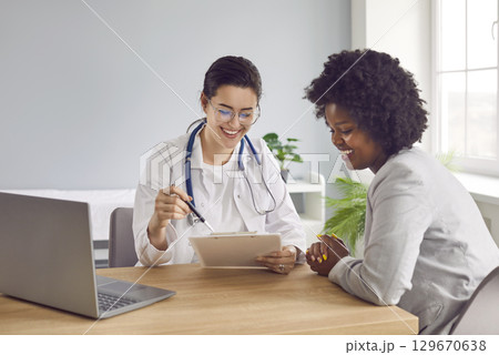 Smiling female doctor giving advice to female patient in medical office 129670638