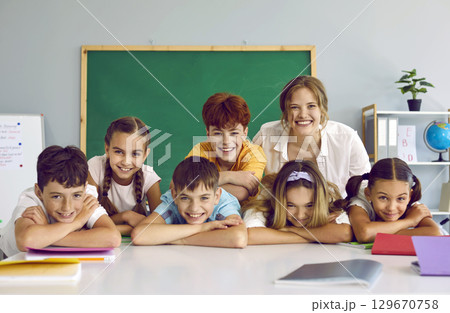 Portrait of cheerful group of elementary school students and their friendly casual female teacher. Portrait of cheerful group of elementary school students and their friendly casual female teacher. 129670758