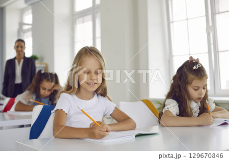 Elementary school children sitting in the classroom and writing in their notebooks Elementary school children sitting in the classroom and writing in their notebooks 129670846