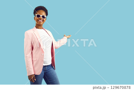 Smiling woman holding open palm with copy space for advertising product or text above it. 129670878