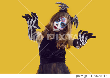Spooky teenage girl behaves like zombie scaring you during Halloween celebration. 129670917