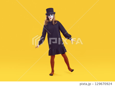 Full body shot of funny child in Halloween costume standing isolated on yellow background 129670924