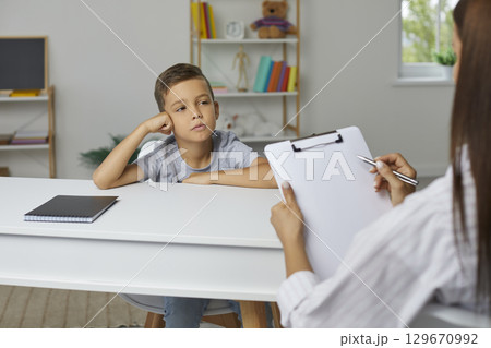 School counselor, psychologist or teacher with clipboard talking to child and taking notes 129670992