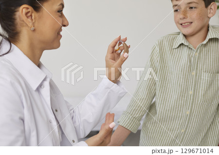 Audiologist gives a hearing aid to a little child patient who experiences hearing loss Audiologist gives a hearing aid to a little child patient who experiences hearing loss 129671014