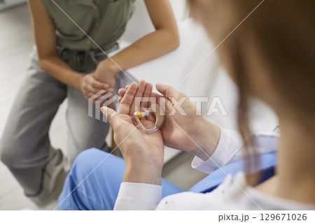 Audiologist gives a modern hearing aid to a little hearing-impaired child patient 129671026