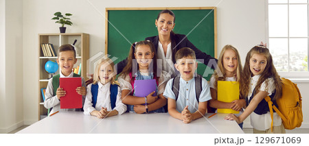 Portrait of female teacher and her little elementary school students on first day of school. Portrait of female teacher and her little elementary school students on first day of school. 129671069