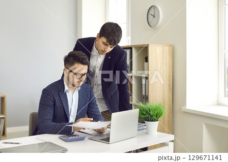 Two employees working in the company office and doing business paperwork together 129671141