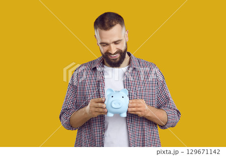 Happy handsome young man holding his piggy bank 129671142