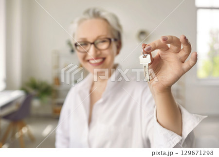 Happy senior middle aged woman customer landlord holding key to new house apartment. Happy senior middle aged woman customer landlord holding key to new house apartment. 129671298