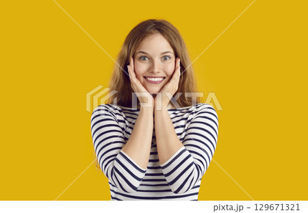 Happy excited young woman waiting for present and looking at camera in anticipation 129671321