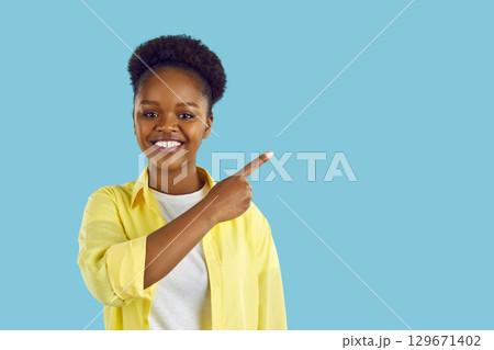 Portrait of attractive cheerful African American woman demonstrating copy empty space for ad advert. 129671402