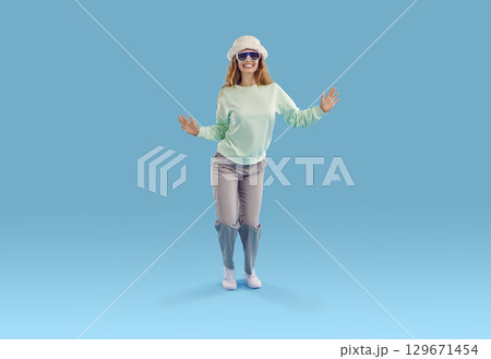 Funny happy young woman in modern casual outfit dancing on blue studio background Funny happy young woman in modern casual outfit dancing on blue studio background 129671454
