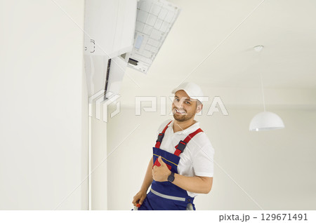Portrait of professional male technician who services and installs modern wall air conditioners. Portrait of professional male technician who services and installs modern wall air conditioners. 129671491