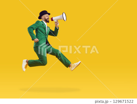 Man with megaphone jumps on copy space background and makes announcement about Patrick's Day party Man with megaphone jumps on copy space background and makes announcement about Patrick's Day party 129671522