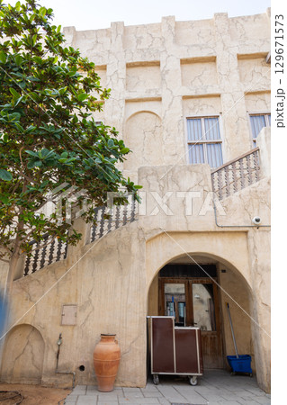 Old town in Al Seef Cultural Historical District on shores of Dubai Creek. Tourist place with old streets, houses and shops, Dubai, UAE. Vertical photo 129671573