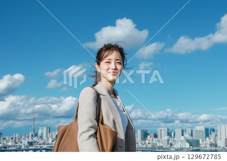 青空と高層ビル群を背景に笑顔の日本人の女性。ビジネスウーマン 129672785