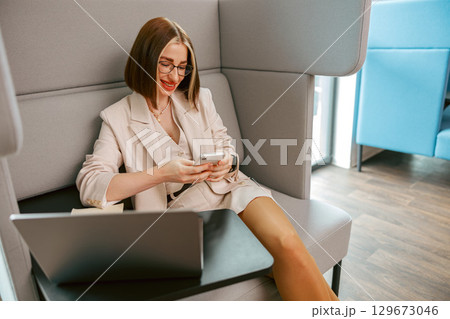 A young professional is utilizing their smartphone in a sleek and modern workspace setting 129673046