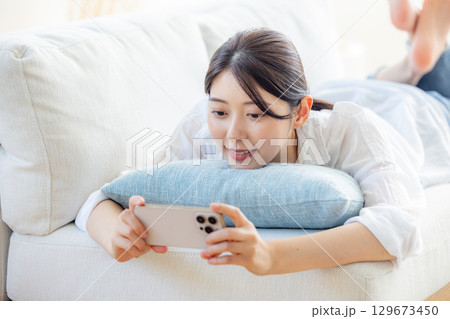 リビングで動画を見る女性 リビングで動画を見る女性 129673450
