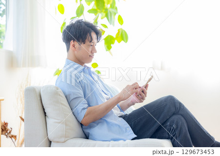 リビングでスマホを使う男性 129673453
