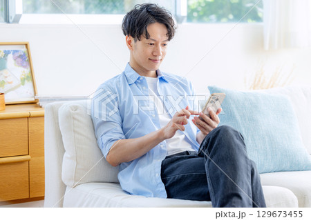 リビングでスマホを使う男性 129673455