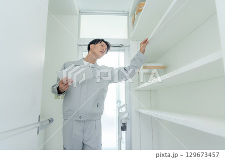 家を点検する作業服の男性 129673457