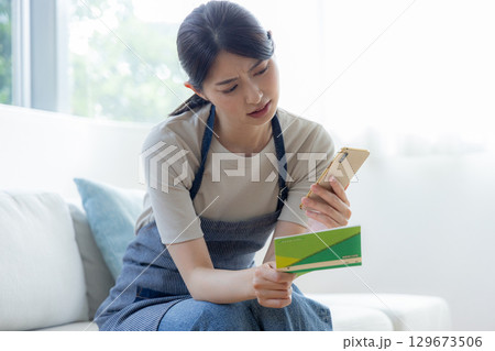 通帳を見ながら悩む女性 129673506