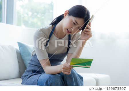 通帳を見ながら悩む女性 129673507