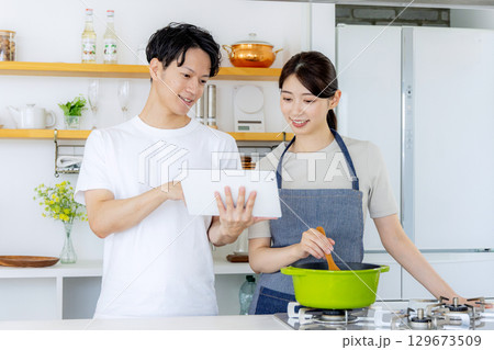 キッチンで料理をする若い夫婦 129673509