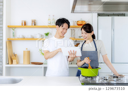 キッチンで料理をする若い夫婦 129673510