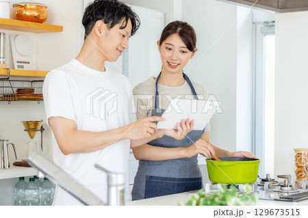 キッチンで料理をする若い夫婦 キッチンで料理をする若い夫婦 129673515