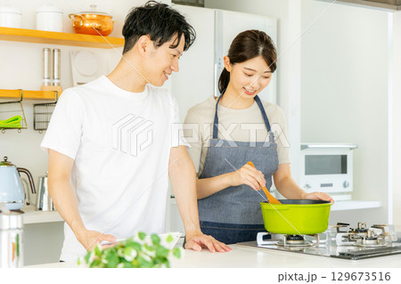 キッチンで料理をする若い夫婦 129673516
