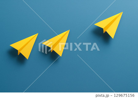 Two yellow airplanes aligned together ahead of a group of white airplanes symbolizing partnership in leadership 129675156