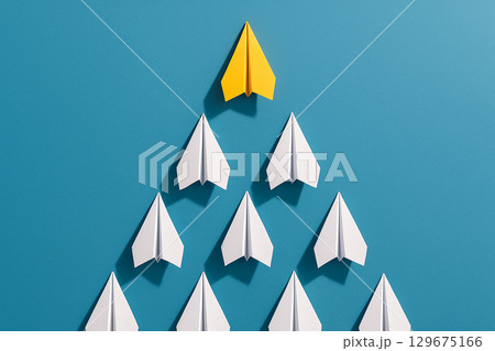 A yellow airplane leading a white triangular group against a blue background to symbolize strategic leadership A yellow airplane leading a white triangular group against a blue background to symbolize strategic leadership 129675166